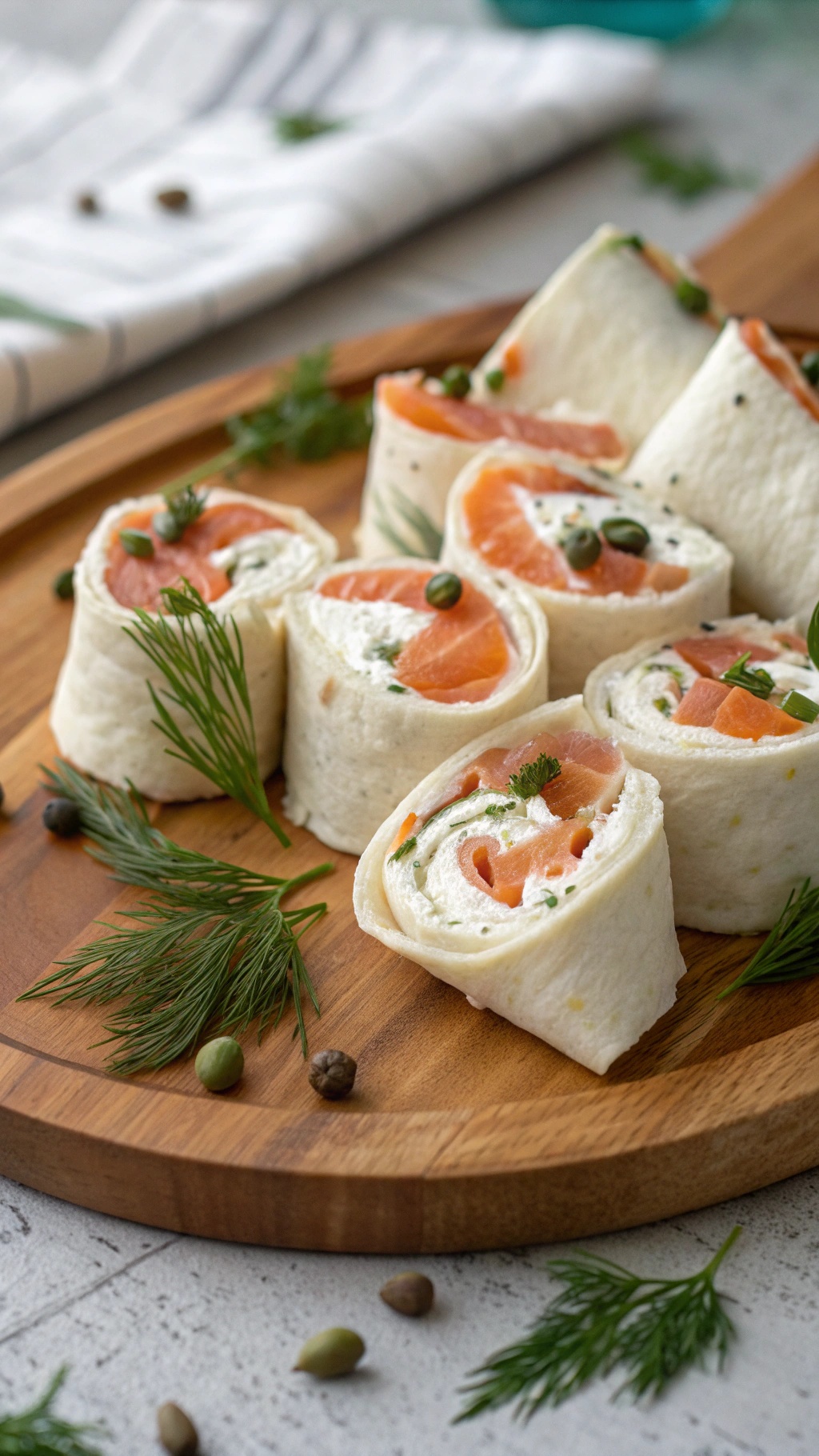 Smoked salmon and cream cheese wraps on a wooden platter, garnished with dill and capers.
