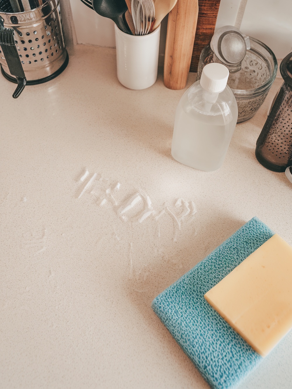 A bottle of dish soap and a sponge on a kitchen countertop, with soap residue visible.