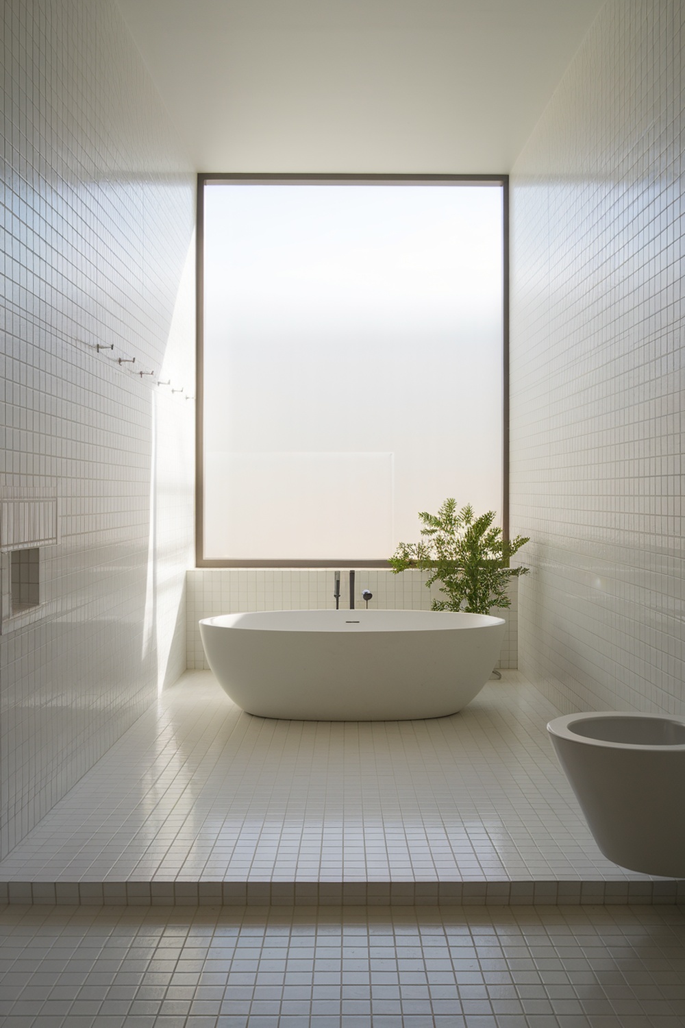 A minimalist bathroom featuring a freestanding bathtub, large window, and greenery.