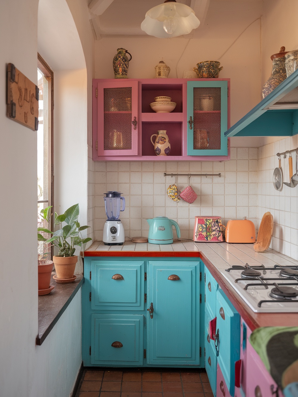 A small kitchen featuring colorful cabinets in pink and turquoise, with a bright atmosphere and cheerful decor.