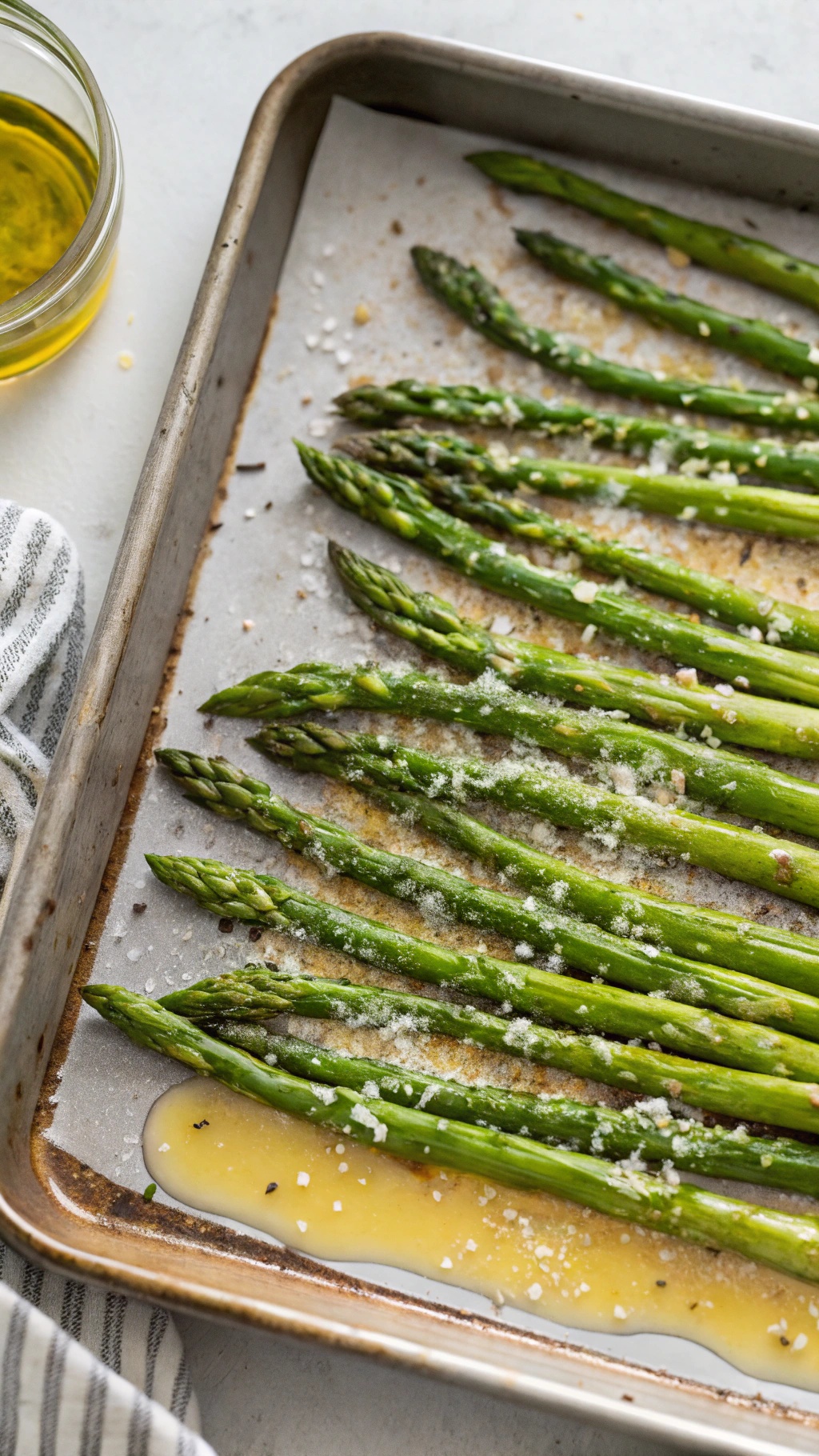 A baking sheet with roasted asparagus drizzled with olive oil and sprinkled with salt.