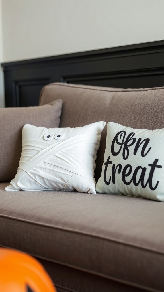 Halloween-themed pillows on a couch, one resembling a mummy and the other with the phrase 'Ofn treat.'