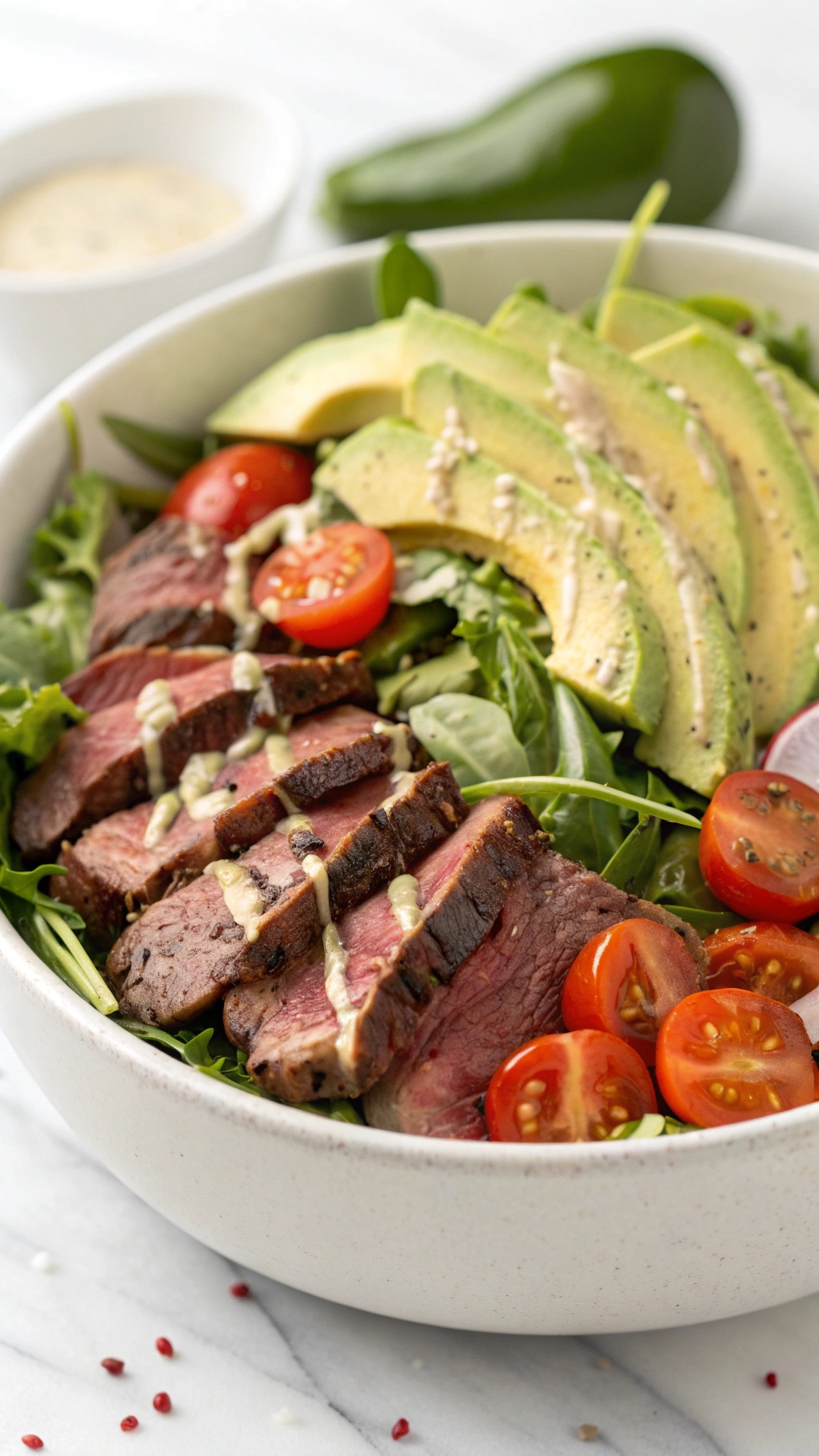 A delicious beef and avocado salad bowl with sliced beef, avocado, cherry tomatoes, and mixed greens.
