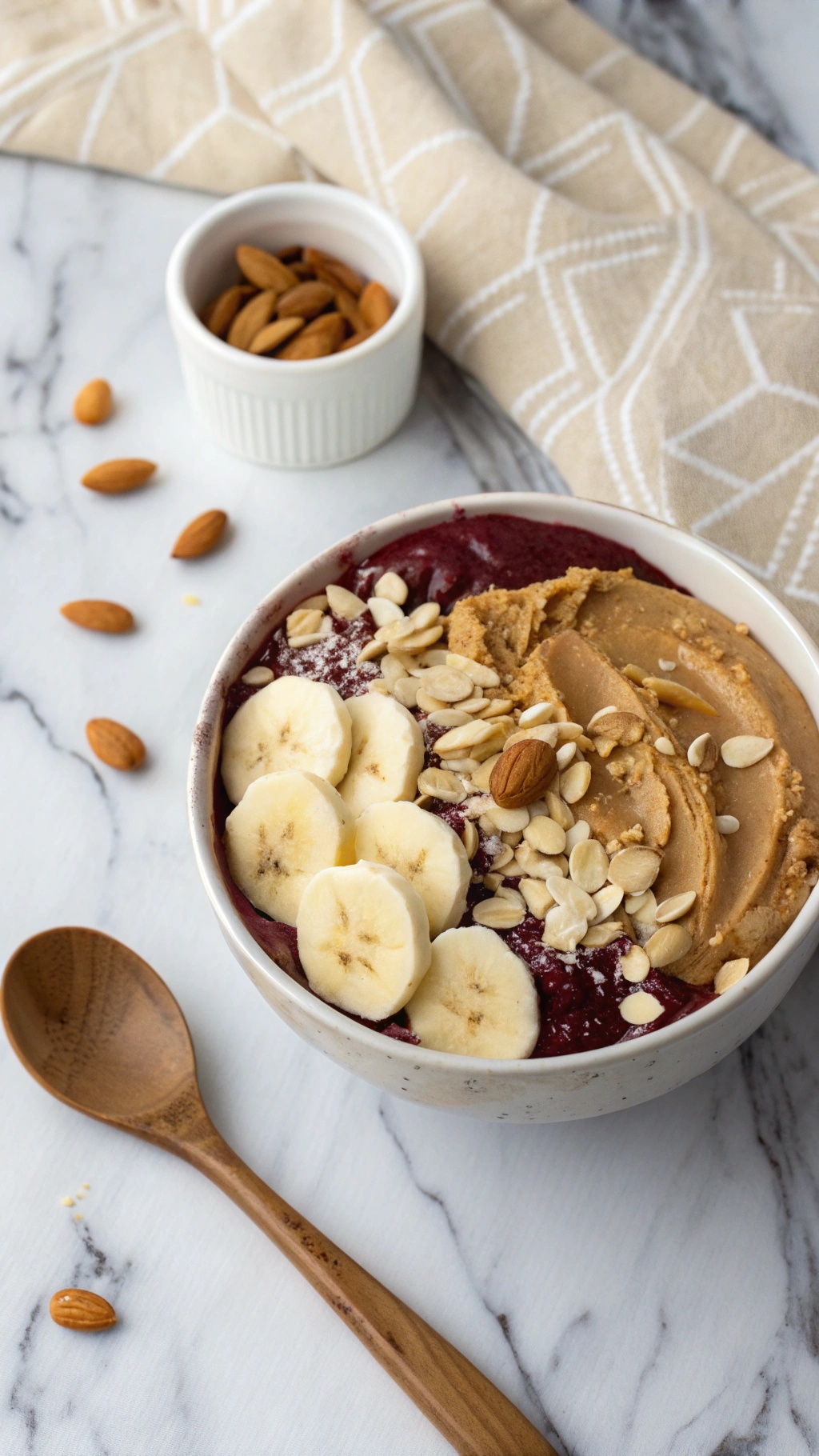 A delicious almond butter acai bowl topped with banana slices, granola, and almonds.