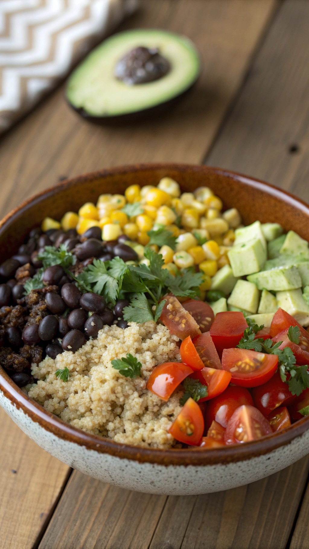 A colorful quinoa and black bean bowl with corn, tomatoes, and avocado.