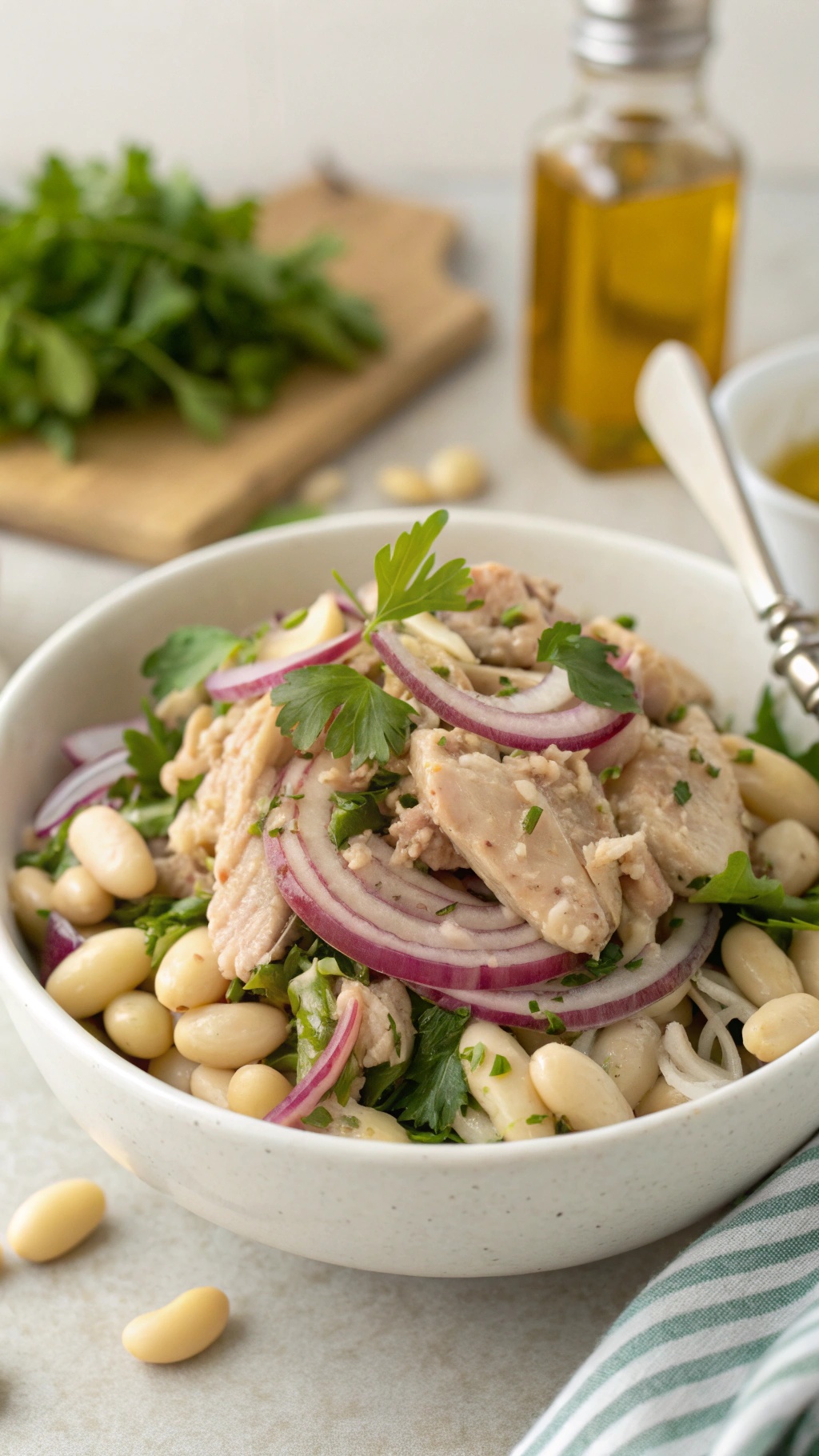 A bowl of Simple Tuna and Bean Salad with tuna, white beans, red onion, and parsley.