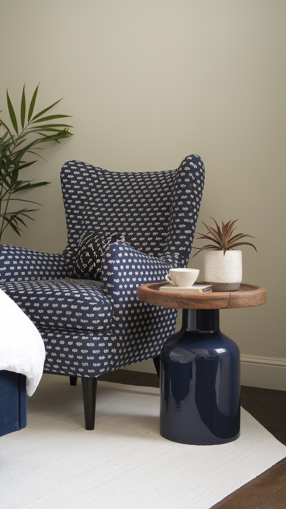A navy blue accent chair with a floral pattern next to a round side table and a small plant.