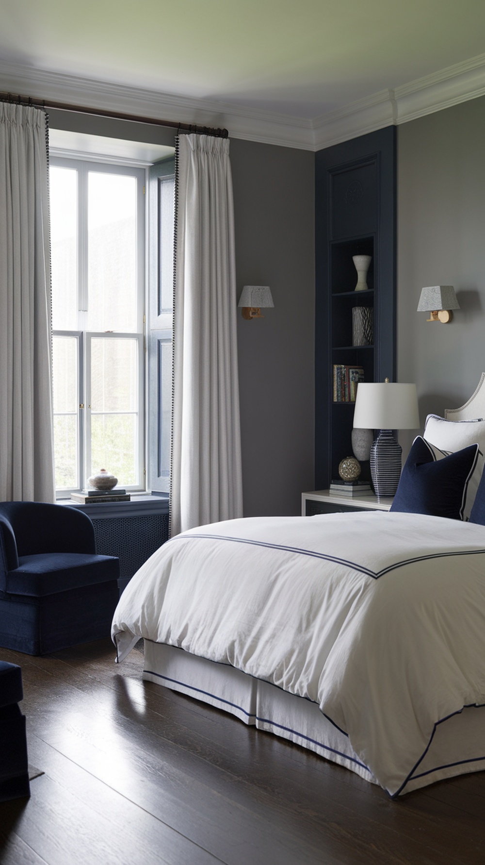 A stylish bedroom featuring navy blue and gray color combinations with white bedding.