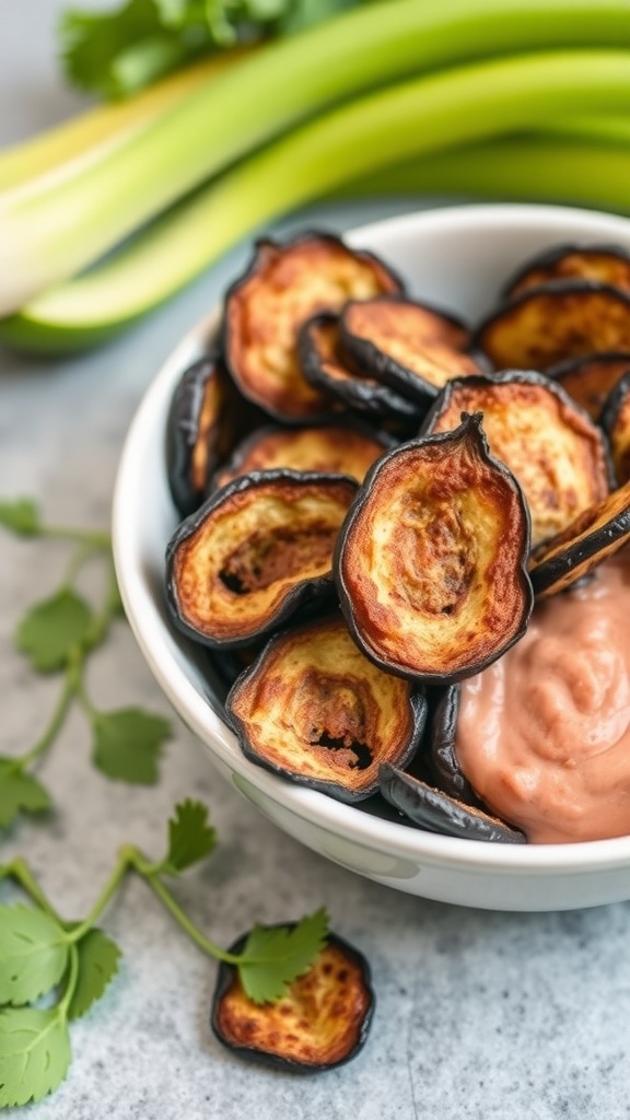 A bowl of baked eggplant chips with a creamy dip, surrounded by fresh celery and cilantro.