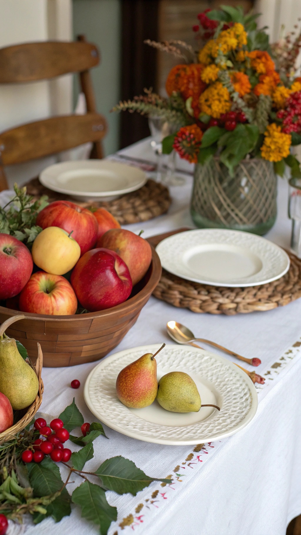 A Thanksgiving table setting featuring a basket of apples and pears, with a floral centerpiece and decorative plates.