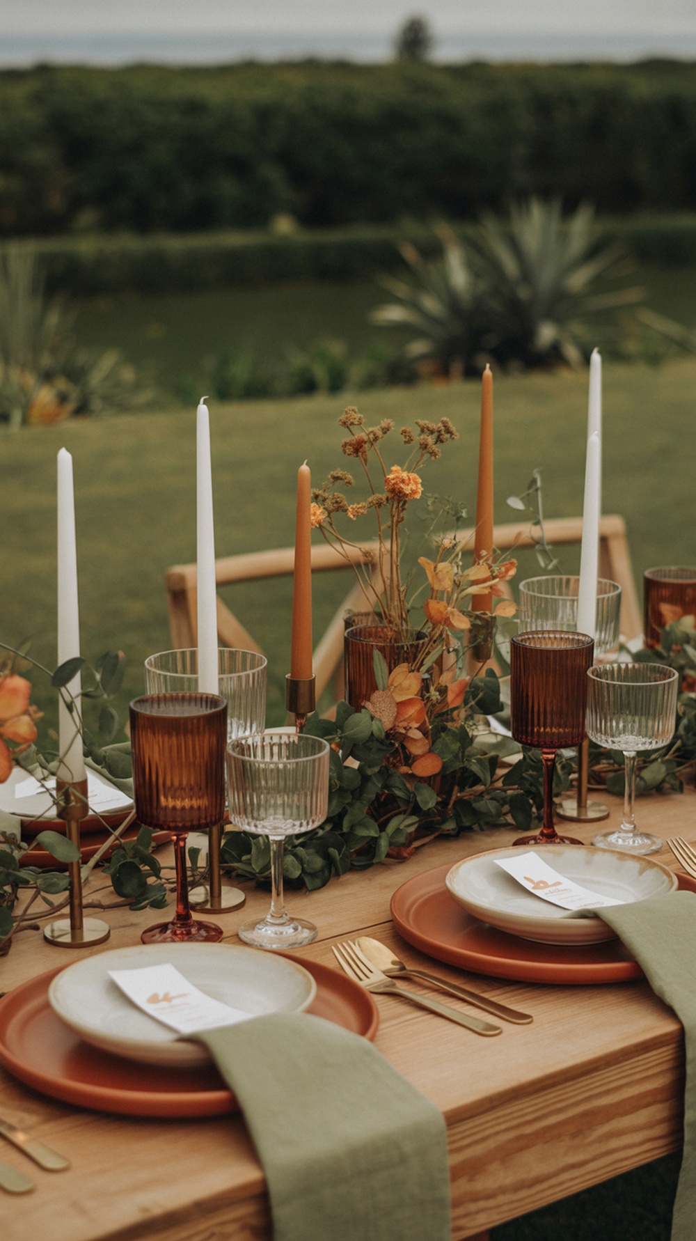A rustic Thanksgiving table setting featuring earthy colors, terracotta plates, green napkins, and candles.