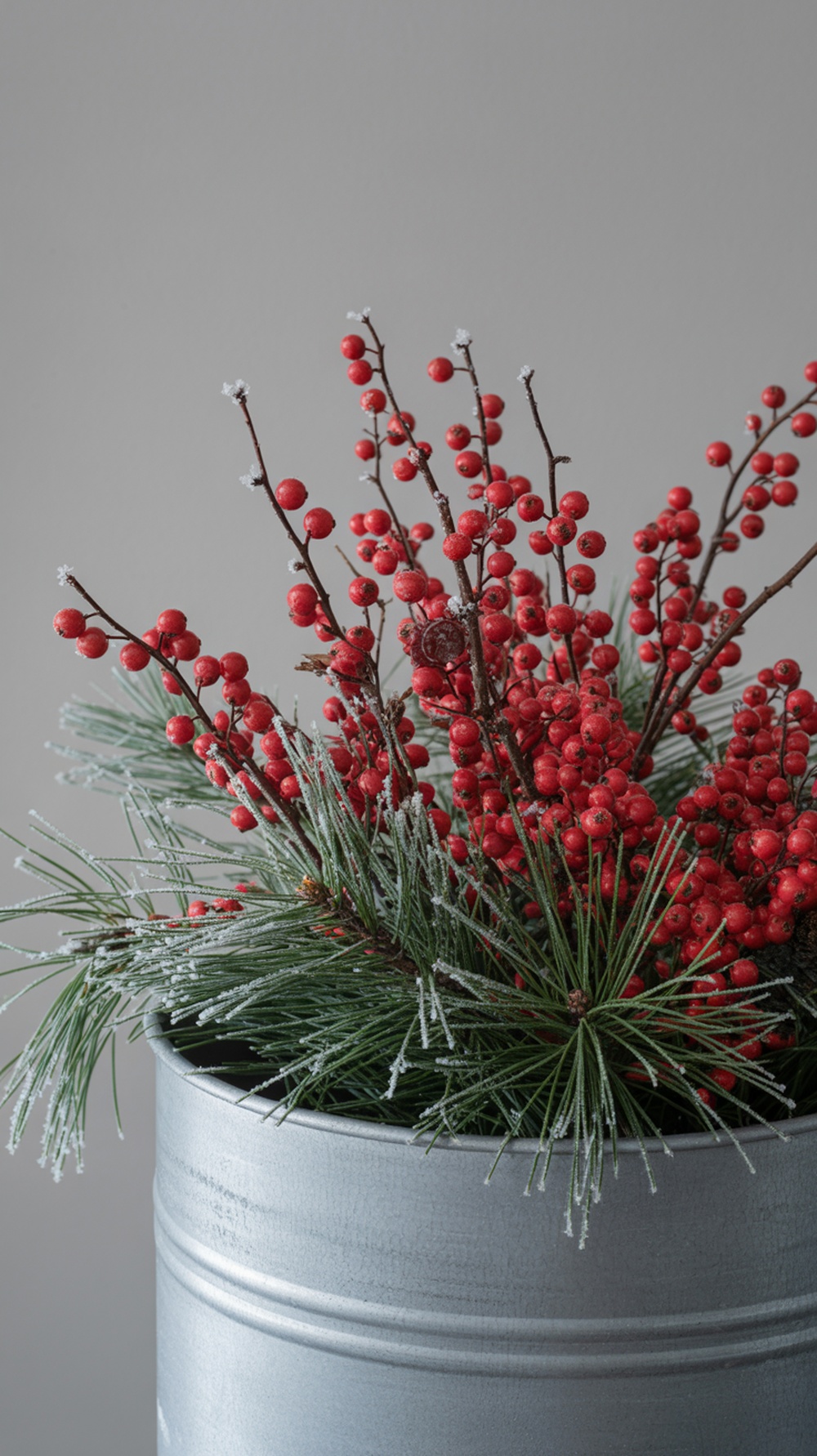 A close-up of a planter filled with red berries and pine branches.