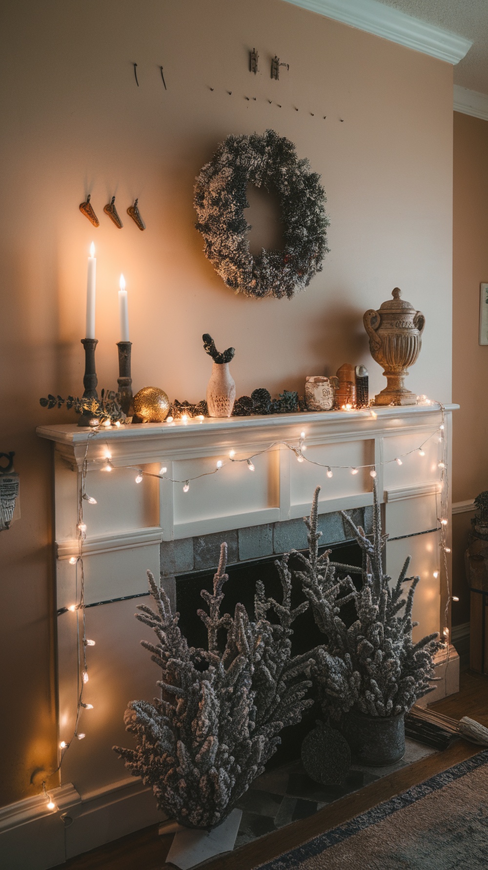 A beautifully decorated mantel for Thanksgiving featuring string lights, a wreath, candles, and frosted plants.