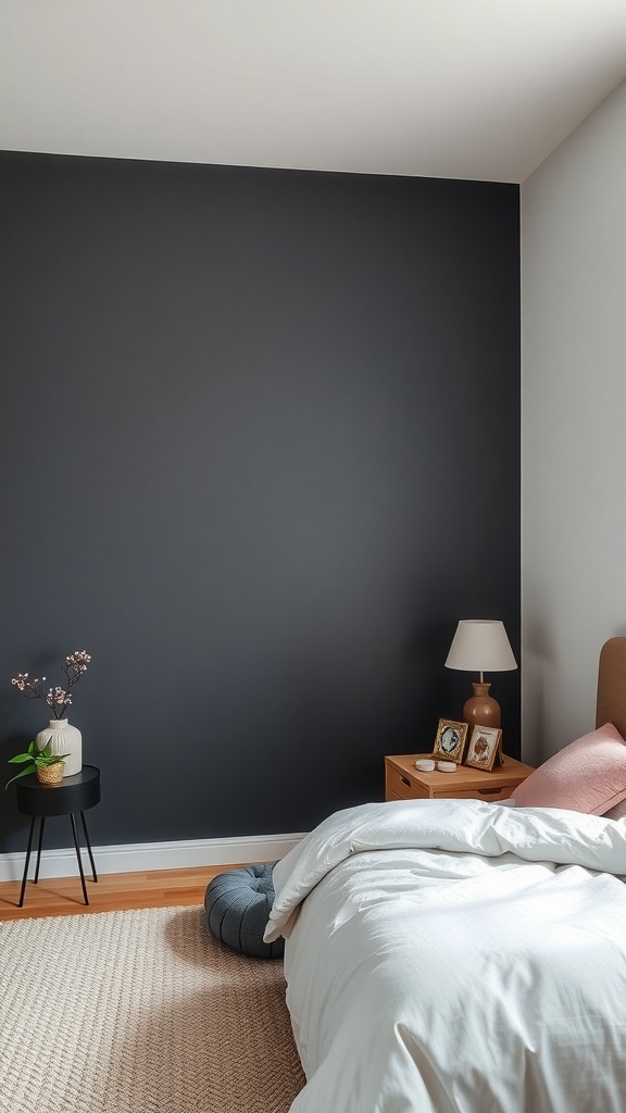 A dark grey accent wall in a bedroom with light bedding and wooden furniture.