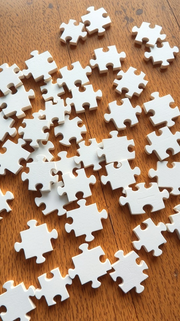 Scattered white puzzle pieces on a wooden surface