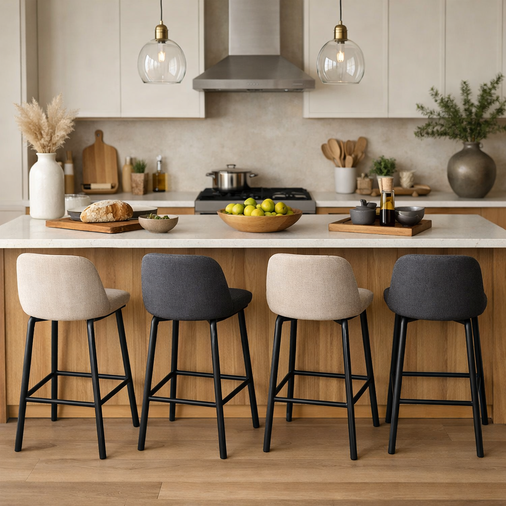 A light brown kitchen island with neutral bar stools, decorated with fresh greens and a loaf of bread.