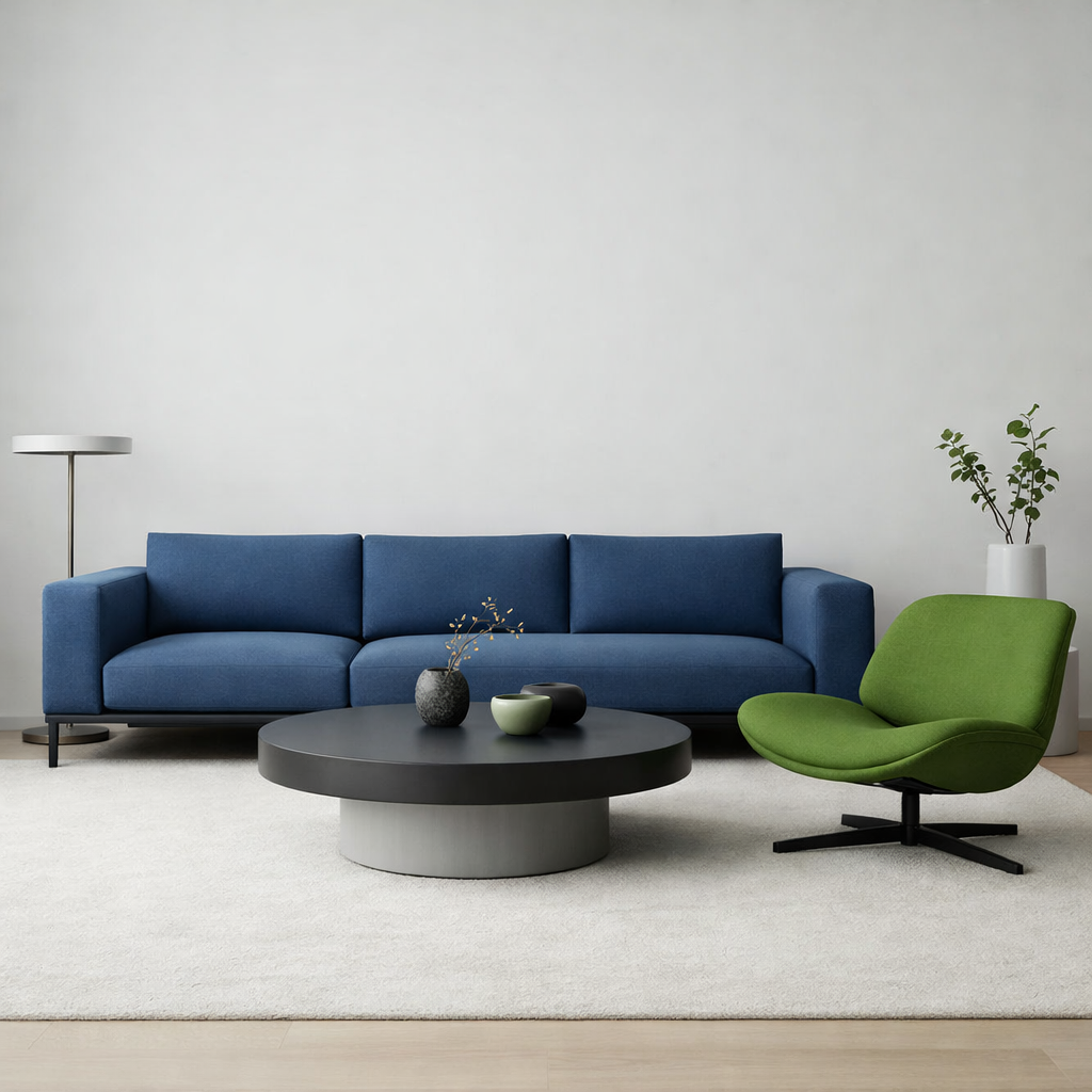 A modern living room with a blue sofa and a green chair, featuring a round coffee table and minimal decor.