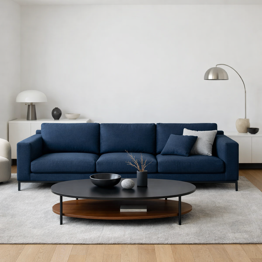A modern living room featuring a dark blue sofa, a minimalist coffee table, and light decor.