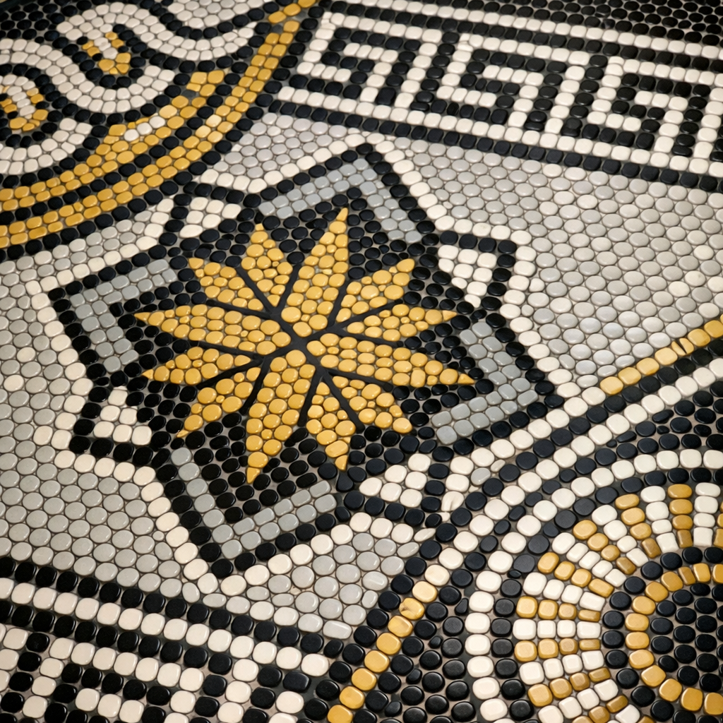 Close-up of penny tile bathroom floor with intricate patterns in black, white, gray, and yellow.
