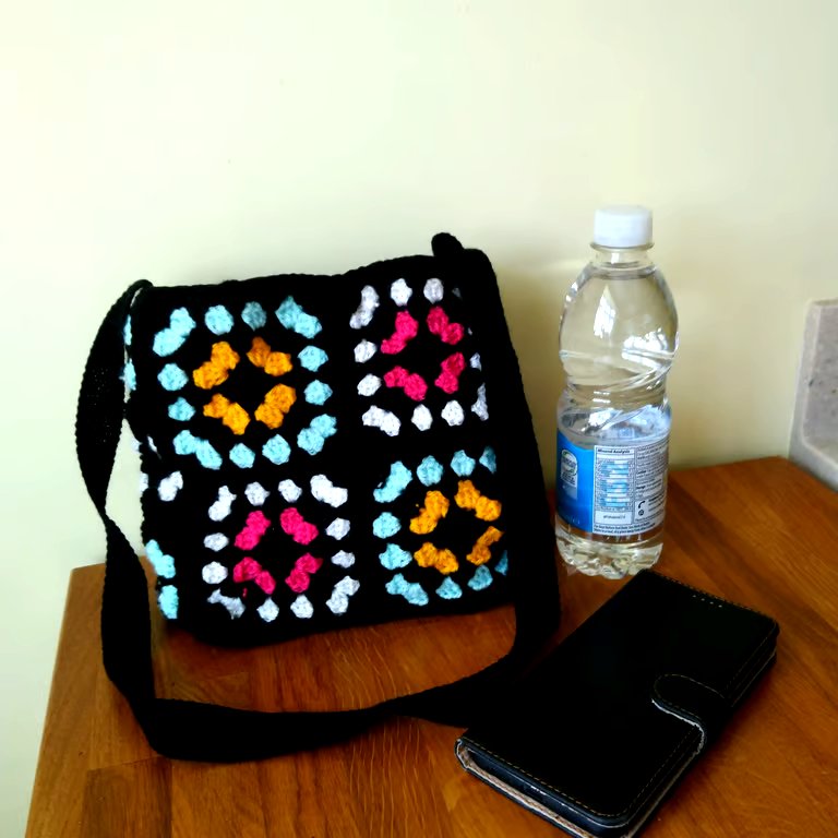 Crochet shoulder bag in black, yellow, green, white & pink granny squares. Lined