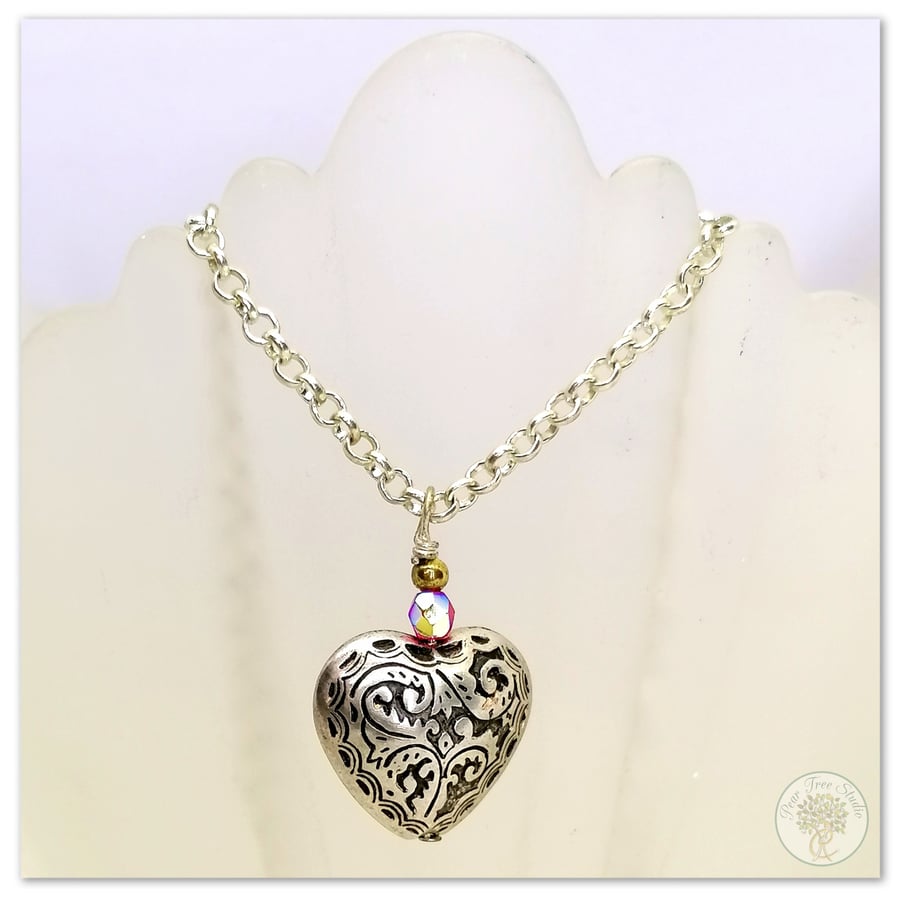 Silver heart necklace with a small red crystal bead on a silver-plated chain.