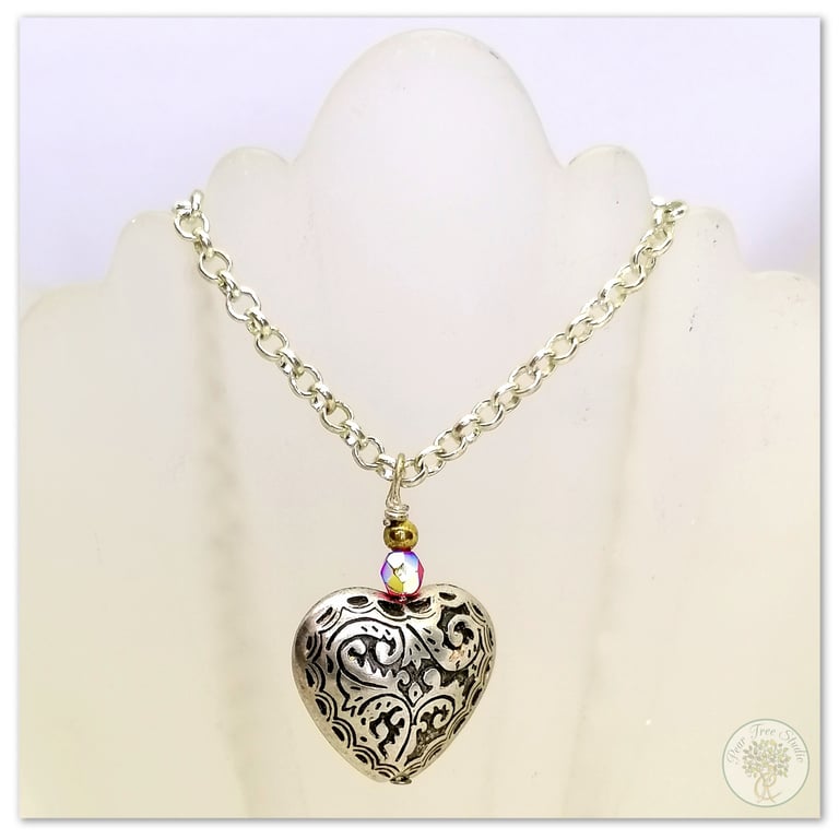 Silver heart necklace with a small red crystal bead on a silver-plated chain.