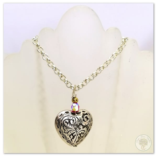 Silver heart necklace with a small red crystal bead on a silver-plated chain.