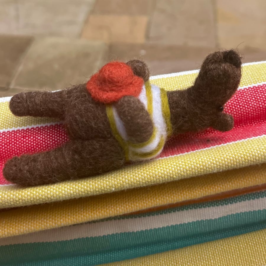 Handmade needle felted brown bear in striped top and holding his hat
