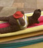 Handmade needle felted brown bear in striped top and holding his hat