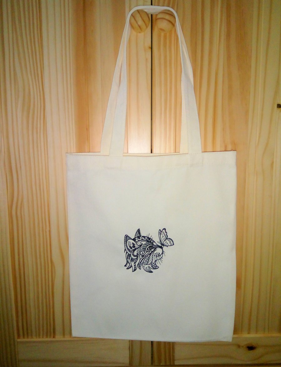 Cat and butterfly embroidered in black on a cream tote bag