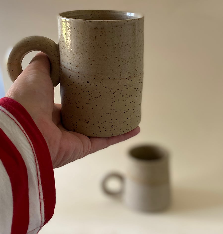 Set of 2 speckled clay mugs with donut handles.