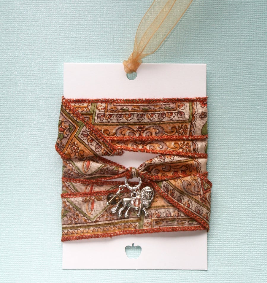 Burnt orange patterned silk ribbon wrap bracelet with lion and glass charms