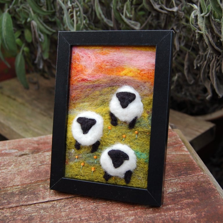 Colourful sheep wool painting.  Needlefelt picture of three sheep and flowers