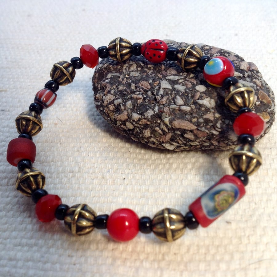 Red and bronze bracelet with collection of beads: ladybird and trade bead