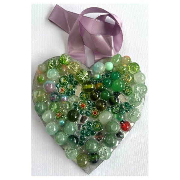 A wooden heart shaped pendant with ocean green coloured spheres and decorations.