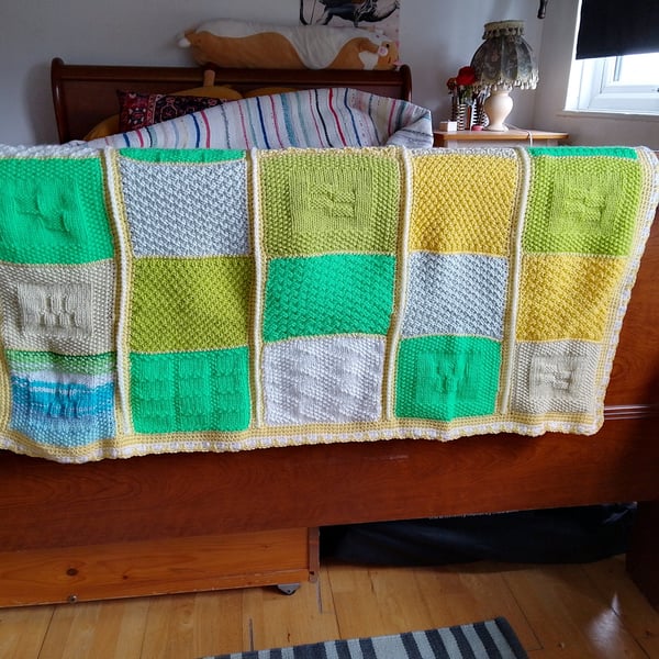 Baby or toddler handmade knitted blanket in a yellow and green theme.