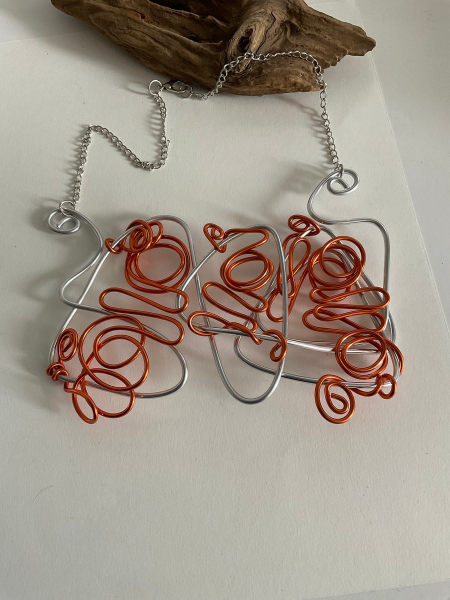 Unique silver and orange coloured wire designer necklace.