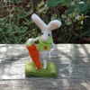 Needlefelt white rabbit wearing a jacket and holding a carrot