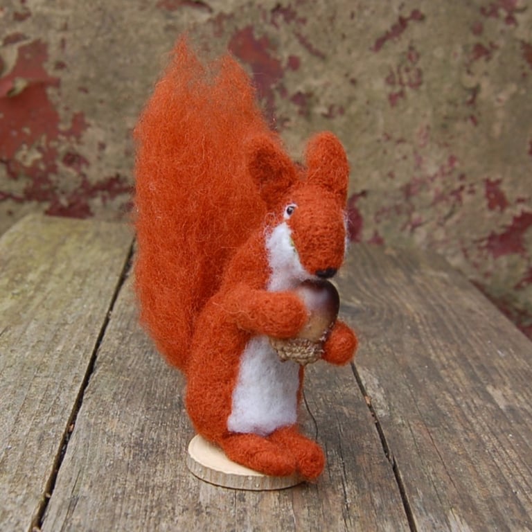 Needle felt red squirrel holding an acorn