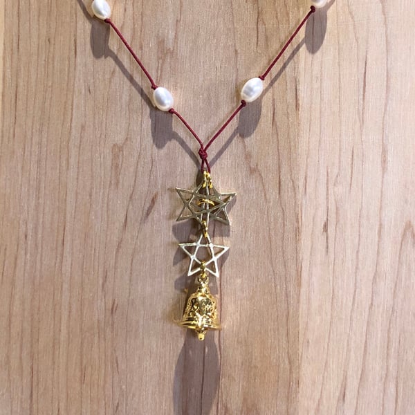 Triple brass star and bell pendant strung with freshwater pearls.