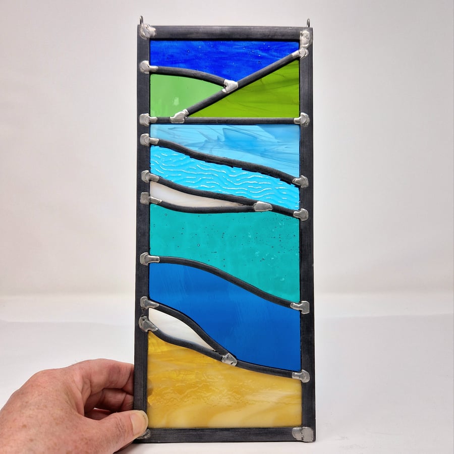 Stained glass beach study seascape in strong colours, leaded hanging panel.