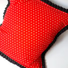 Red polkadot cushion cover with black polkadot pleated edge.