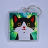 LITTLE BLACK AND WHITE HAPPY CAT KEYRING WITH GREEN BACKGROUND