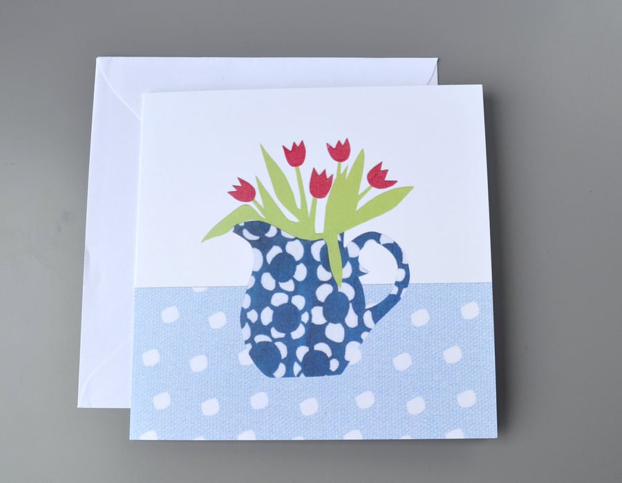 Jug of red tulips in a blue and white patterned jug on spotty tablecloth card