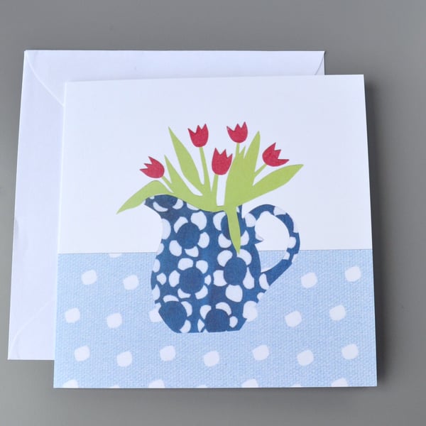 Jug of red tulips in a blue and white patterned jug on spotty tablecloth card