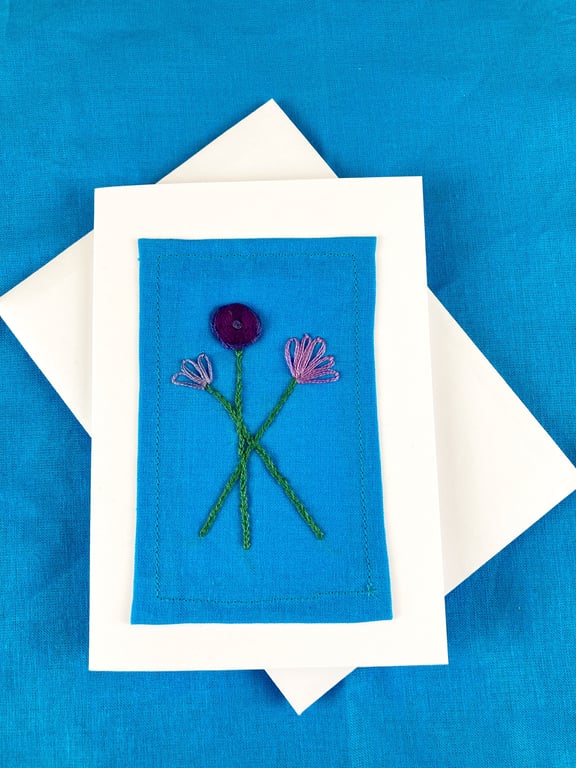 A trio of purple flowers embroidered card.