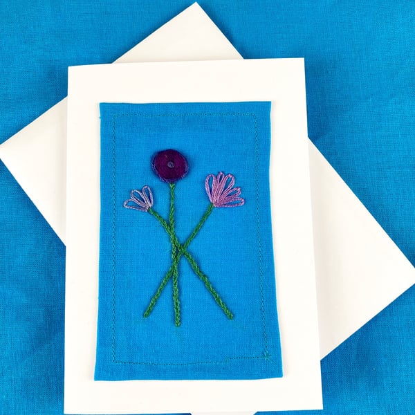 A trio of purple flowers embroidered card.