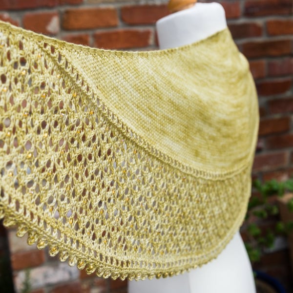 Shawl hand knit in a crescent shape using a green yellow coloured soft yarn