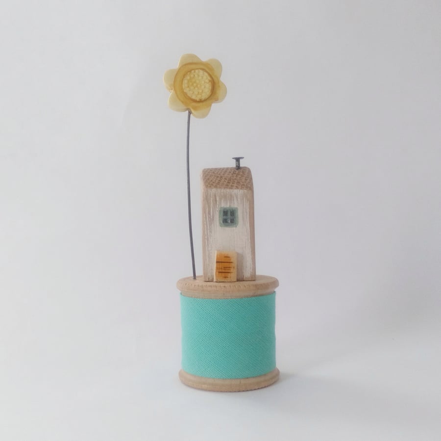 Tiny oak house with clay flower on vintage wooden bobbin