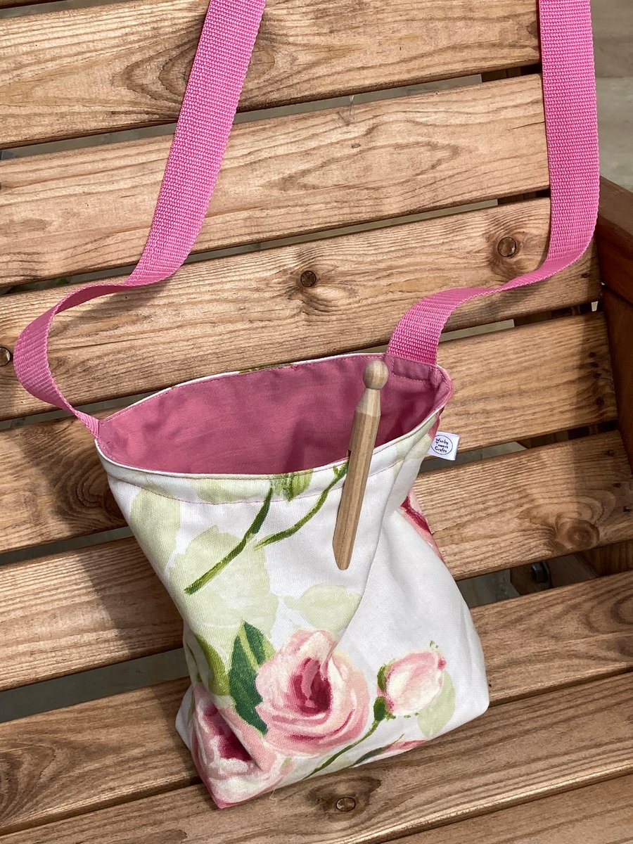 Pretty, floral peg bag with pink shoulder strap. Traditional rose design.